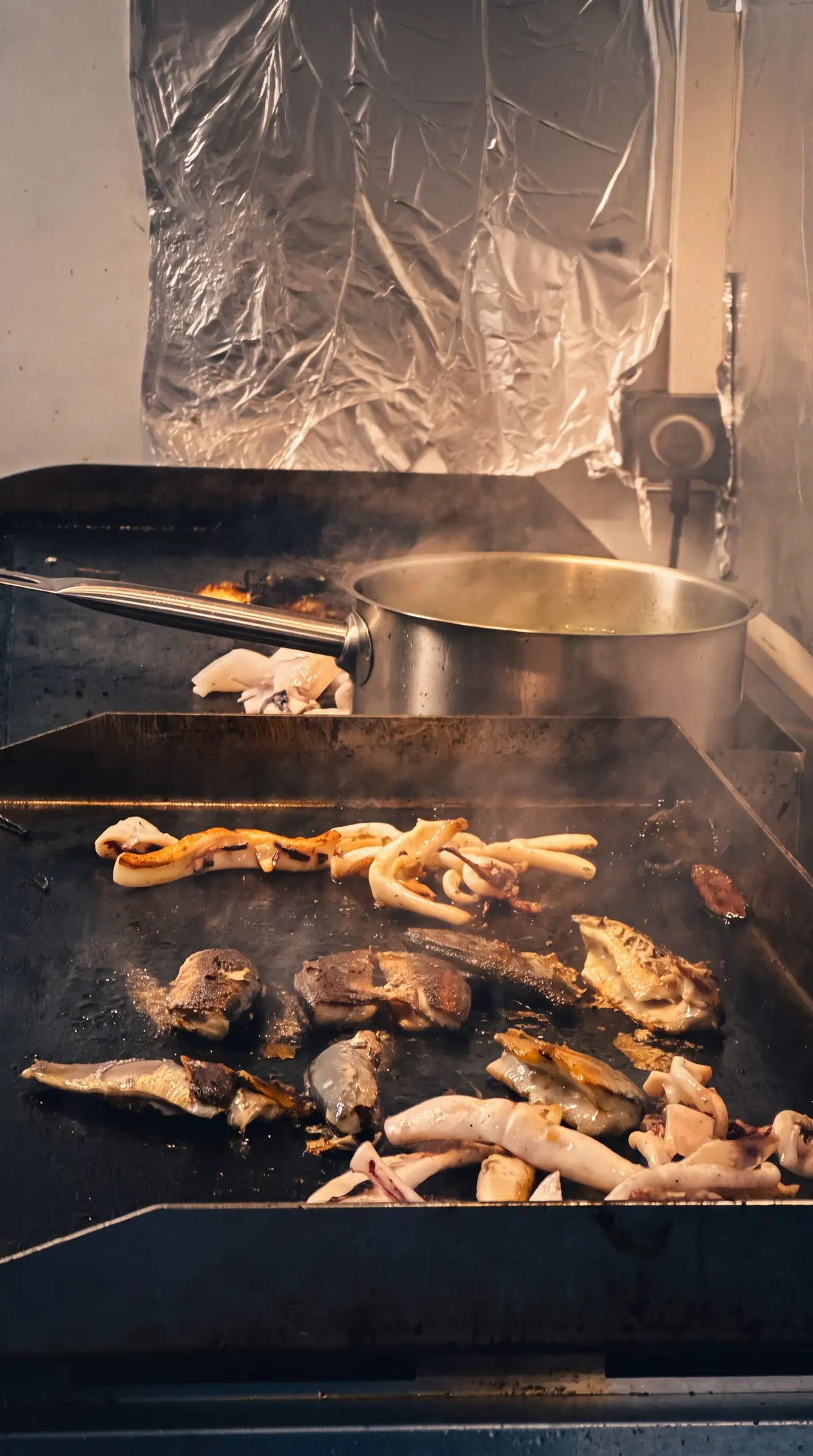 Calamars et poissons qui grillent sur la plancha du camion.